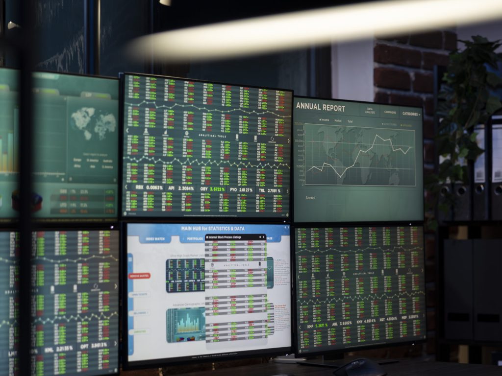 Vacant workstation with multiple monitors displaying forex charts, arranged in a modern office for traders. Computer screens showing financial data, ready for night shift employees.